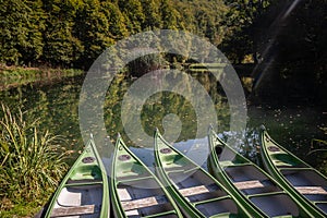 Panorama of the pond Jankovac with plastic canoe and kayak in front of a small water lake surrounded by trees and forest in the