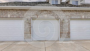 Panorama Puffy clouds at sunset Garage exterior with bricks and three white sectional doors