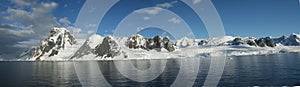 Panorama - Reflections of glacial icefalls and mountains, with cloudy blue sky