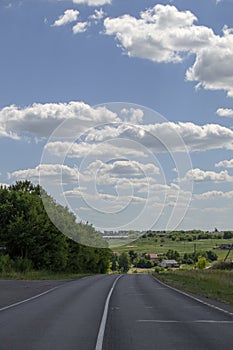 Panorama of the road in the summer evening asphalt road and on the sides of green trees