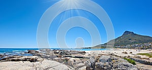 Panorama of a rocky beach near the ocean and mountain on a sunny day in South Africa. Landscape wallpaper of a coastline