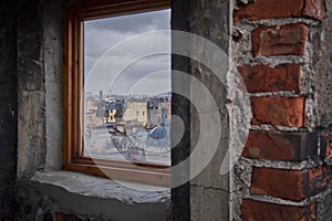 Panorama of the roofs of the old city. View of the city through the attic window. Cloudy weather.