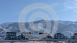 Panorama Row of houses against snow dusted hills and blue sky on a gloomy winter day