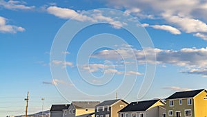 Panorama Row of houses under a vibrant blue sky with fluffy clouds on a sunny day