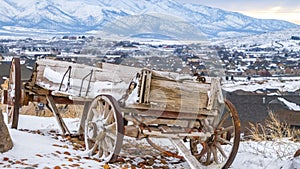 Panorama Rustic wooden wagon beside a huge rock on top of a snowy hill in winter