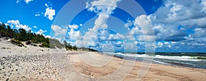 Panorama of sand dunes, sea waves and blue sky in a summer morning