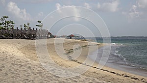 Panorama of the sandy beach with chaise lounges and sunshades in the tropical resort. Bali. Indonesia