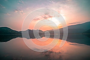 Panorama scenic of mountain lake with perfect reflection at sunrise. beautiful mountain range landscape with pink pastel sky with