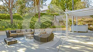 Panorama Seating area on the patio of a house surrounded by lush foliage and metal gate