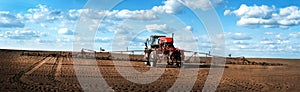 Panorama of self-propelled red sprayer in the field makes fertilizers in early spring