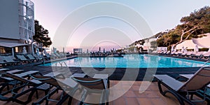 Panorama shot of swimming pool and chaise lounges