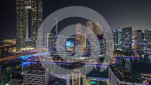 Panorama showing Dubai Marina with several boat and yachts parked in harbor and skyscrapers around canal aerial night