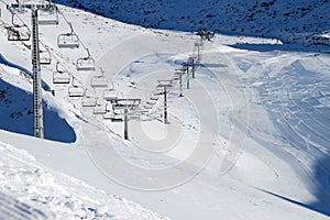 Panorama of ski resort, slope, people on the ski lift, skiers on the piste among white snow pine trees