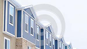 Panorama Snowy gable roofs at the facade of townhome with brick wall and vertical siding