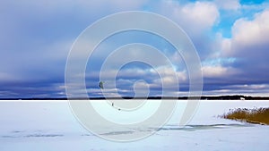 Panorama of snowy lake with lonely sportsman doing winter kiting