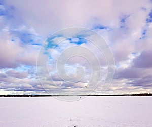 Panorama of snowy lake with lonely sportsman doing winter kiting