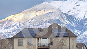 Panorama Solar panels on roof of home with lake and snowy mountain background in winter