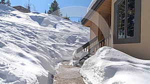 Panorama Stone brick pathway and stairs leading to home entrance amid deep layer of snow