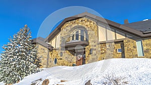 Panorama Stone home with small balcony over front door decorated with wreath in winter