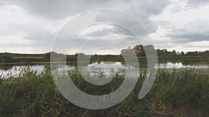 Panorama of storm clouds over a small summer pond in evening