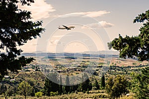 Panorama of the suburbs of the Greek city of Athens with landing plane at sunset