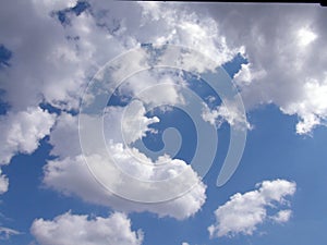 Panorama of the summer morning sky covered with snow-white clouds illuminated by the rays of the sun.