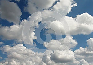 Panorama of the summer morning sky covered with snow-white clouds illuminated by the rays of the sun.