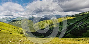 Panorama of summer mountains under blue cloudy sky