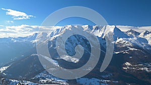 Panorama from summit on snow capped mountain peaks and ridges of the italian Alps in winter season, clear sunny sky.