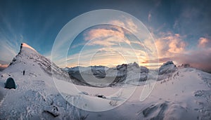 Panorama of sunrise over snowy mountain range with mountaineer tent camping in winter on Segla Mount at Senja Island