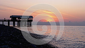 Panorama of the Sunset over the Sea next to the Silhouette of the Pier.