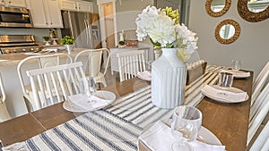 Panorama Table setting inside a dining room with brown table and white chairs