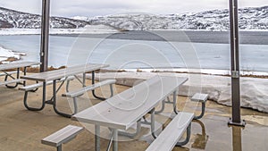 Panorama Tables and benches inside a pavilion overlooking an icy lake with snowy shore