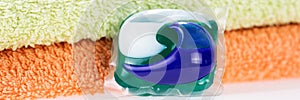 Panorama. Three in one eco gel capsule laundry detergent in front of two towels