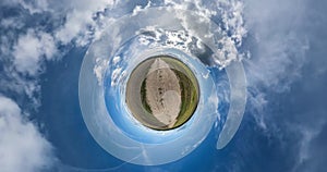 Panorama of tinyl planet transformed into a spherical panorama rotates among the blue sky with clouds