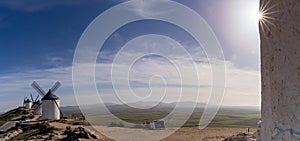 Panorama of traditional whitewashed Spanish windmills in La Mancha on a hilltop above Consuegra with a sun star