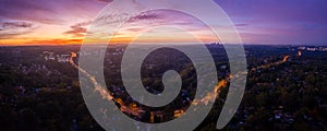 Panorama of traffic light trails on Ryde Road at dawn snaking through Pymble with the sunrise silhouetting the Sydney CBD in the