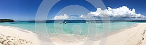 Panorama of two boats anchored to turquoise waters off a white sand beach under a blue sky in Abaco, Bahamas photo