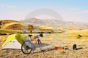 Panorama of unloaded touring red bicycle by green tent. Camping and bicycle touring concept Travel around Armenia by bicycle in
