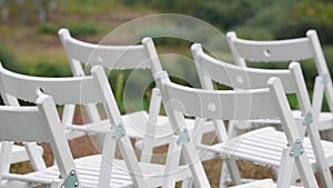 Panorama of the variety of white folding chairs in the area of marriage registration at the wedding ceremony with drops