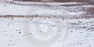 Panorama view from above on texture of snow covered gravel dirt road in the forest