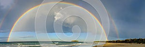 Panorama view across Mystics Beach, Killalea, NSW of double rainbow