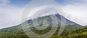 A panorama view of the Arenal volcano with cloud cover at the summit in Costa Rica