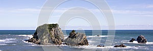 Panorama view on the beautiful New Zealand west coastal area, with the Tasman Sea, rocks, blue water and a clear sky.