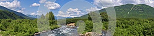 Panorama view of beautiful summer landscape - stream water of mountain river and green forest on sunny day with white