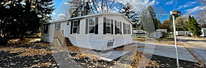 Panorama view brand new prefab mobile home with for sale yard sign post, colorful fall foliage in Rochester, New York