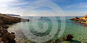 panorama view of an idyllic cove at Es Cap Enderrocat in southern Mallorca with a sailboat at anchor