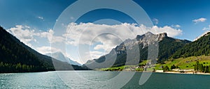 Panorama view of an idyllic and picturesque turquoise mountain lake surrounded by green forest and mountain peaks in the Swiss