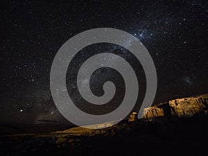 Panorama view of milkyway stars in dark night sky above cliff rock formation in Uyuni Sur Lipez Bolivia South America