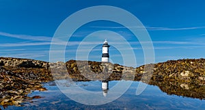 Panorama view of the Penmon Lighthouse in North Wales with relfections in a tidal pool